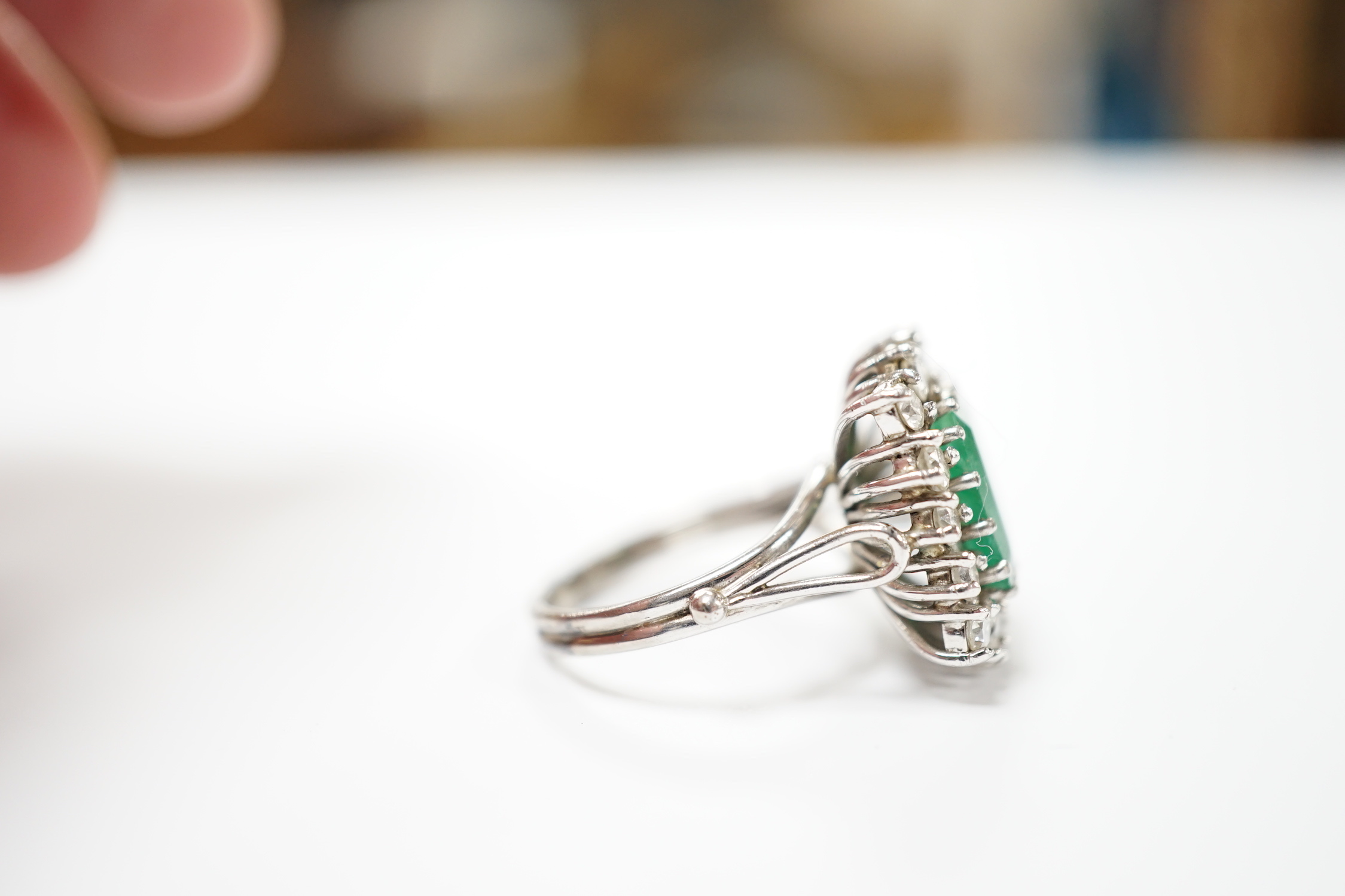 A white metal, emerald and diamond set square cluster ring, size I, gross weight 6.3 grams.